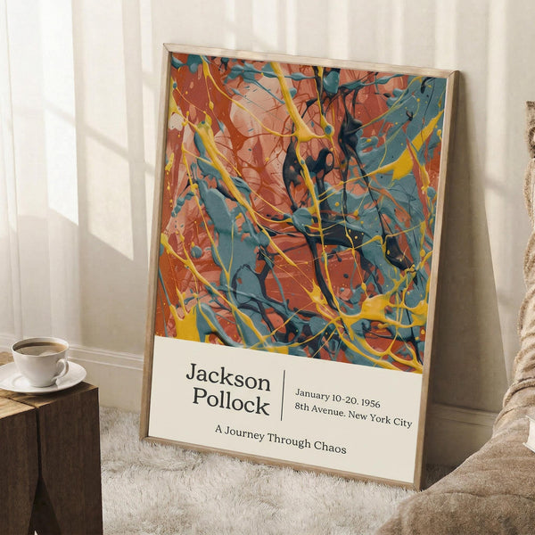 May include: Abstract expressionist poster with vibrant orange, teal blue, and yellow paint splatters and drips in chaotic patterns, displayed in thin wooden frame leaning against white wall. White coffee cup on wooden surface nearby, textured cream rug below, soft natural lighting creating shadows.