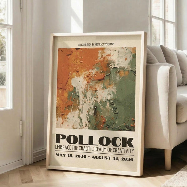 May include: Framed abstract art exhibition poster with orange, green and white paint splashes in Jackson Pollock style, displayed on light wooden floor against white wall corner. Gray upholstered sofa with pillows visible on right side. Natural sunlight streaming through tall windows creates soft shadows on wall. Poster features bold black text beneath colorful abstract artwork section.