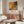 a modern living room with a large abstract painting on the wall, a wooden cabinet, a white sofa, and a glass coffee table.