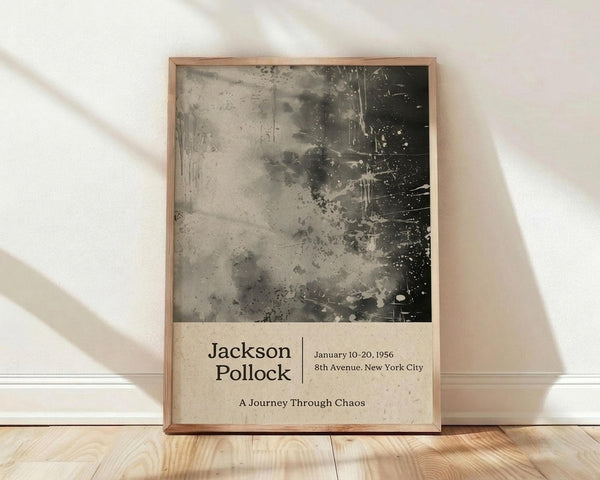 May include: Framed poster with abstract black and gray paint splatters in Jackson Pollock's drip painting style, displayed against white wall on light wood floor. Poster features exhibition-style text layout with artist name, dates, location, and subtitle below the artwork. Natural wood frame with warm lighting casting diagonal shadows across the scene.