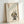May include: Framed poster print featuring a cute black cat with large yellow eyes and pink inner ears sitting next to green bamboo stalks, with Japanese characters and a red stamp at the top, displayed in a light wooden frame against a white wall and surface in soft natural lighting.