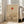 May include: Minimalist Japanese-inspired art print in light wood frame leaning against white wall beside beige upholstered chair. Artwork features warm beige background with red-orange sun, curved lines, silhouetted bare tree, and large tan circle. Natural lighting from tall windows creates soft shadows on hardwood floor.