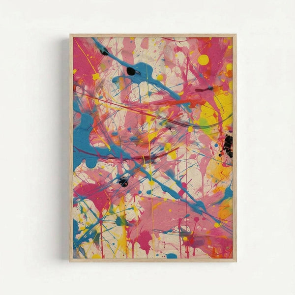 Abstract expressionist artwork featuring energetic paint splatters, drips, and gestural brushstrokes in vibrant pink, blue, yellow, black, and white. Dynamic lines and color patches create movement across the composition, with paint drips and splashes scattered throughout. The piece is displayed in a light wooden frame against a white wall, showcasing the spontaneous, action-painting style with overlapping colors and bold gestural marks.