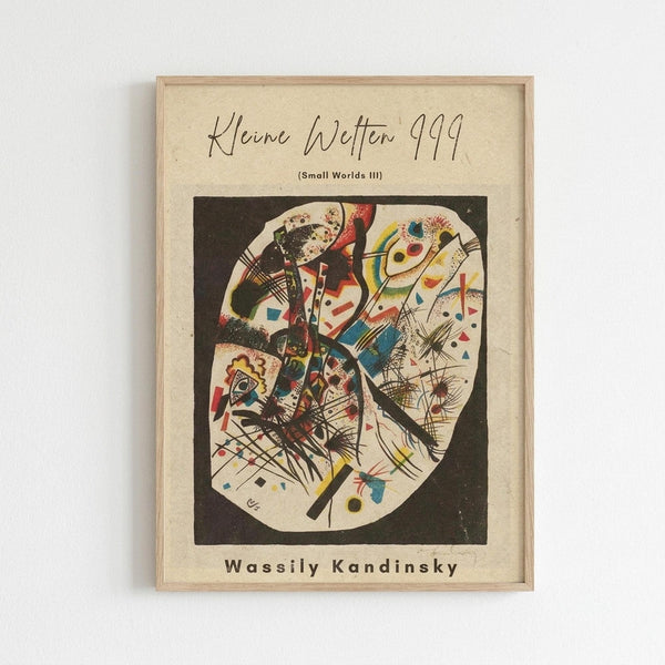 Abstract geometric artwork featuring bold lines, shapes, and vibrant colors including red, blue, yellow, and green arranged in a circular composition against a black background. The piece displays Kandinsky's characteristic abstract expressionist style with intersecting angular forms, dots, and dynamic linear elements. Framed in natural wood and displayed on a white wall, showing the cream-colored mat border around the colorful print.