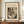 May include: Framed abstract art print featuring Wassily Kandinsky's colorful geometric composition with curved forms, lines, and shapes in red, blue, yellow, and black tones. The beige poster displays "Kleine Welten 999" and "Small Worlds III" text above the artwork. Shown in wooden frame on walnut credenza beside white ceramic vase and stacked books against cream wainscoted wall.