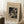 May include: Abstract geometric artwork print in warm beige mat and light wood frame, leaning against white wall corner. Black and white modernist design features angular shapes, celestial elements, and intricate patterns. Artist name "Wassily Kandinsky" printed below image. Small wooden side table with white coffee cup visible on left. Cream textured rug and neutral bedding create cozy room setting with natural window lighting.