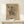 May include: Framed abstract art print by Wassily Kandinsky featuring geometric black line drawings on beige background, displayed on light wood console table with small white wrapped gift beside it against cream wall
