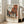 May include: Framed art print of Johannes Vermeer's Dutch Golden Age painting showing red brick buildings along a cobblestone street with small figures, displayed in a bright modern living room with beige sofa, large windows, and light wooden floors.