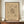 May include: Framed abstract art print in warm beige tones featuring geometric lines, dots, and angular shapes in black ink. The minimalist poster displays intricate linear patterns radiating from a central composition, surrounded by smaller scattered elements. Shown in thin brown frame on wooden sideboard next to white ceramic vase and stacked books in bright room with white walls and crown molding.