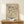 May include: Framed abstract art print in light wood frame leaning against white wall on rustic wooden surface. Black line drawing on beige background features geometric shapes, curved lines, dots, and angular forms in Kandinsky's distinctive abstract style. Small white wrapped gift with twine and greenery sits beside frame. Warm, minimalist home decor setting with natural wood textures.
