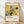 May include: Framed Japanese art print leaning against white wall on light wood floor. Yellow-toned artwork shows detailed hydrangea flowers with dark green leaves and a black swallow bird in flight. Modern wooden frame surrounds the vintage botanical illustration. Soft natural lighting creates diagonal shadows across the scene.