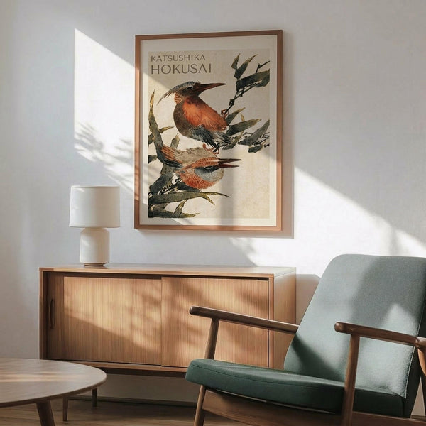 May include: Framed vintage Japanese woodblock print featuring two colorful birds perched on flowering branches, displayed above a mid-century modern wooden credenza with lamp in bright living room setting with sage green upholstered chair