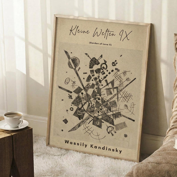May include: Framed abstract art print leaning against white wall corner on textured cream rug. The beige poster features black geometric and organic shapes in an explosive, dynamic composition. A white coffee cup sits on a wooden block nearby, with soft natural lighting creating shadows across the minimal room setting.