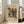 May include: Abstract art poster with colorful geometric shapes, lines, and patterns in yellow, red, teal, and black on cream background, displayed in light wood frame leaning against white wall next to beige couch in bright room with large windows and natural lighting on hardwood floors.