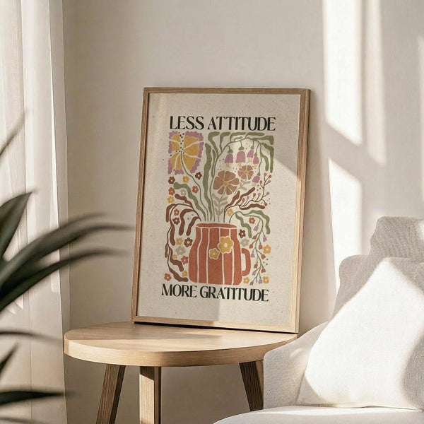 May include: Framed motivational poster with decorative floral design featuring a coffee mug with colorful botanical elements flowing from it, displayed on a round wooden side table next to a beige upholstered chair. Warm natural lighting creates soft shadows on white walls, with a plant visible in the corner of the cozy living room setting.