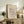 May include: Framed abstract art print with geometric black line drawings on cream background, displayed on rustic wood sideboard with fern plant, leather chair, books, and ceramic vase in warm neutral living room setting