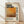 May include: Framed poster with Mark Rothko's name in bold black letters, featuring an abstract painting with warm orange and brown tones that fade from bright yellow-orange at top to darker earthy browns below. The years 1903-1970 appear vertically along the right side. Descriptive text about the artist sits below the artwork. The cream-colored poster is displayed in a thin wooden frame, leaning against a white wall on light wooden flooring with soft natural lighting.