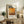 May include: Framed poster print featuring Mark Rothko's name in bold black text with abstract orange and brown painted artwork and dates. Displayed on rustic wooden sideboard next to fern plant, ceramic vase, and stacked books in neutral-toned living room with beige armchair and pillows.