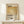May include: Framed Mark Rothko exhibition poster with warm golden-yellow rectangular color field, displayed on light wood surface against cream wall. Small wrapped gift box with twine sits beside the natural wood frame. Poster features black typography and descriptive text about the artist's emotional use of color.