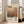 May include: Framed art print leaning against white wall next to beige sofa in bright living room. Poster features abstract brown and orange rectangular color blocks with "Mark Rothko" text and biographical information. Light wood frame, natural lighting from large windows, hardwood floors visible.