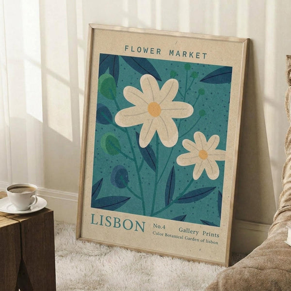 May include: Framed botanical poster with white daisies and blue-green foliage on turquoise background, text reading "Flower Market" and "Lisbon," leaning against white wall corner next to wooden side table with white coffee cup and saucer, cream textured rug beneath
