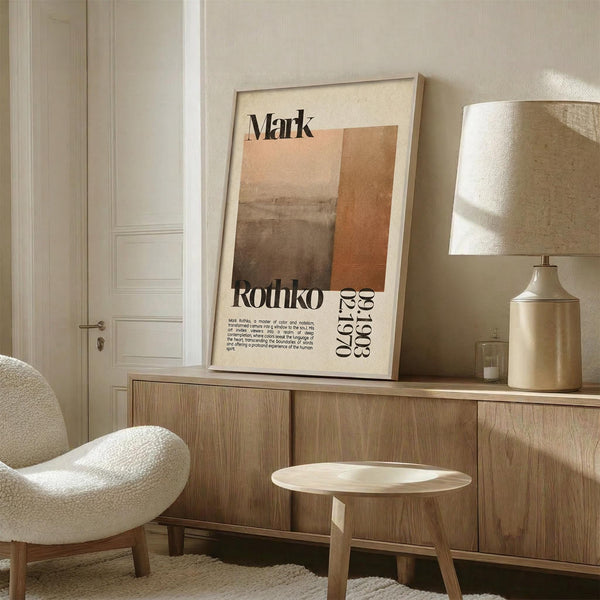 a living room with a large framed poster of an abstract painting hanging on the wall, a white armchair, a wooden sideboard, and a small round table.