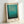 May include: A framed art print featuring Mark Rothko's abstract color field painting with gradual transitions from light turquoise at the top through deeper teal tones to dark navy at the bottom. The print is displayed in a natural wood frame with white matting, leaning against a white wall on a light surface. The artwork shows soft, blended horizontal bands of blue and green hues creating a serene, meditative composition typical of Rothko's style.