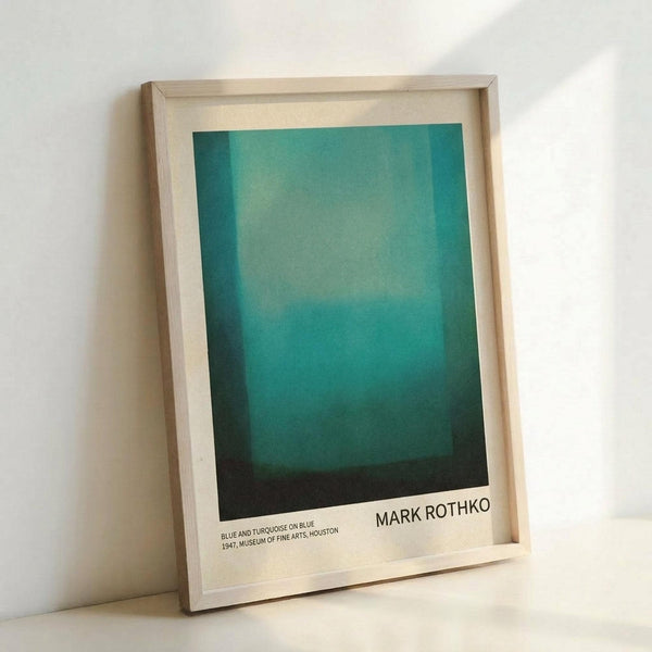 May include: A framed art print featuring Mark Rothko's abstract color field painting with gradual transitions from light turquoise at the top through deeper teal tones to dark navy at the bottom. The print is displayed in a natural wood frame with white matting, leaning against a white wall on a light surface. The artwork shows soft, blended horizontal bands of blue and green hues creating a serene, meditative composition typical of Rothko's style.