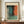 May include: Large framed abstract art print in warm wooden frame, displaying soft rectangular color blocks in coral orange, teal blue, and sage green with blended edges. Positioned on mid-century walnut credenza alongside white ceramic vase and stacked books in bright interior with white paneled walls.