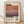 May include: Framed art poster featuring Mark Rothko's name in large black text above a horizontal color-blocked painting with warm orange, pink, and deep burgundy tones. Below shows "Rothko" and dates "1903-1970" in black typography with descriptive text about the artist. Light wood frame against cream background, displayed on wooden floor with soft natural lighting and shadows.