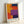 May include: Abstract geometric composition with bold color blocks in orange, red, purple, and navy blue arranged in rectangular sections, displayed in a light wooden frame leaning against a white wall. The artwork shows painterly textures and overlapping color fields in Rothko's characteristic style.