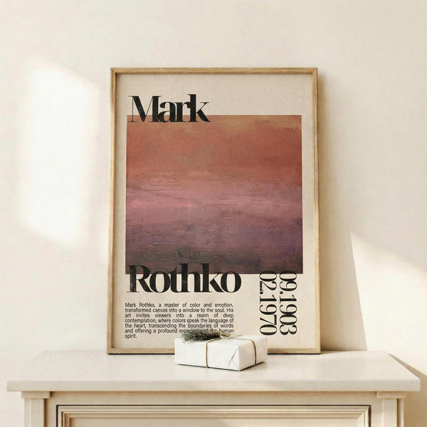 May include: Framed art poster featuring Mark Rothko's name in bold black letters above horizontal bands of warm gradient colors transitioning from cream to coral to deep burgundy, with "Rothko" and "1903-1970" text below. Light wood frame displayed on white wooden surface against cream wall, with small wrapped gift box nearby.