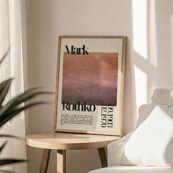 May include: Framed art print featuring Mark Rothko's name and exhibition details with a gradient abstract painting in warm coral, orange, and purple tones. The poster is displayed on a round wooden stool next to a beige upholstered chair with plant shadows cast across white walls in natural sunlight.