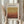 May include: Person holding framed art poster featuring warm gradient bands transitioning from golden yellow at top to deep rust red at bottom. White matted frame with exhibition text for Mark Rothko show at gallery in New York City. Dried wheat stems visible beside frame. Person wears cream colored shirt with gathered cuffs against neutral background.