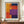 May include: Framed abstract art print with bold geometric color blocks in orange, red, purple, navy blue, and yellow arranged in rectangular sections. The poster features "MARK ROTHKO" text at bottom and is displayed in a thin wooden frame on a walnut credenza beside a small white ceramic vase and stacked books against cream walls with white wainscoting.