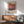 a living room with a wooden cabinet, a green armchair, and a wooden coffee table. Above the cabinet, there is a framed poster of Rothko, a famous abstract expressionist painter.