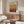 a modern living room with a large wooden cabinet, a white sofa, and a glass coffee table. A framed poster of Mark Rothko hangs on the wall above the cabinet.