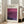 May include: Framed exhibition poster featuring Mark Rothko artwork with deep purple and magenta color fields. Light wood frame leaning against white wall next to beige upholstered chair in bright, airy living room with large windows and natural sunlight streaming across hardwood floors.