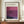 May include: Framed exhibition poster featuring Mark Rothko's abstract color field painting in deep purples and magentas, displayed on a wooden sideboard next to a white ceramic vase and stacked books. The poster shows gallery information and dates from April to July 2023. Warm beige walls with white molding create an elegant interior setting.