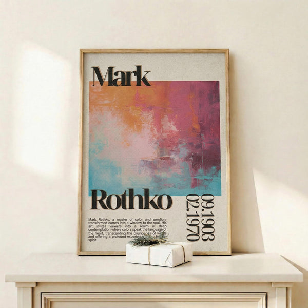 May include: Framed art print featuring abstract watercolor artwork in orange, pink, and teal tones with "Mark Rothko" text and descriptive paragraph below. Light wood frame displayed on white wooden shelf beside small wrapped gift with twine. Cream colored wall background with soft natural lighting.