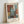 May include: Framed abstract art print leaning against white wall, featuring geometric blocks in muted tones of rust orange, sage green, cream, and gray with soft, painterly edges. Light wooden frame with white matting displays French text at top and artist quote below the artwork.