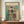 May include: Abstract art poster in wooden frame displaying geometric blocks in muted teal, orange, yellow and burgundy tones with "MARK ROTHKO" text at top, displayed on wooden sideboard next to white ceramic vase and books against cream wainscoted wall