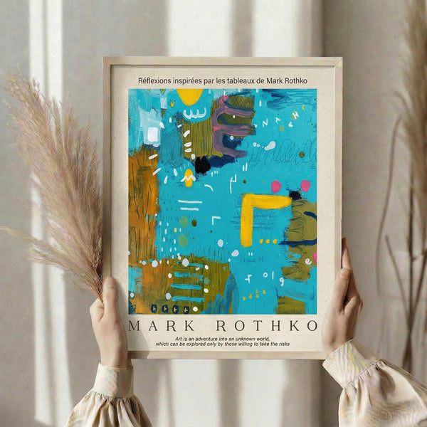 May include: Person holding framed abstract art print in light wooden frame against white curtained window. Artwork features vibrant turquoise blue background with yellow, orange, and purple geometric shapes, white dots and marks scattered throughout. Person wears cream ribbed sweater with puffy sleeves, holds dried pampas grass in other hand. Soft natural lighting creates shadows on white walls.