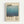 Framed poster featuring a gradient blue abstract painting reminiscent of Mark Rothko's style, with "Mark Rothko" text at top and bottom of the design. The artwork shows soft blue tones transitioning from light to dark, displayed in a light wood frame against a white wall. Small descriptive text appears in the lower left corner of the poster.