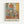 Abstract painting featuring geometric shapes in muted tones of coral, sage green, golden yellow, and warm browns. Layered rectangular and square forms create a composition reminiscent of bottles or vessels, rendered in soft, translucent washes. The artwork has a dreamlike quality with overlapping forms and gentle color transitions. Displayed in a light wood frame against a white wall, with French text below reading "L'abstraction émotionnelle à la manière de Mark Rothko" and "MARK ROTHKO&