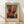 May include: Framed abstract art poster featuring geometric red, orange, and black rectangular shapes with soft, blurred edges against a muted gray-green background. The print has aged, vintage-style coloring and includes Mark Rothko's name and an inspirational quote at the bottom. Displayed in a thin wooden frame leaning against a white wall on light wood flooring with natural sunlight casting diagonal shadows across the scene.