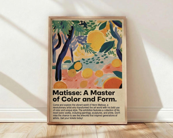 May include: Framed poster with colorful tropical scene featuring yellow sun, green palm fronds, orange citrus fruits, and coral pink brushstrokes in Matisse-inspired style. Black text below reads "Matisse: A Master of Color and Form" with exhibition description. Natural wood frame sits on light wooden floor against white wall with soft shadows.
