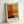 May include: Framed abstract art print in light wood frame leaning against white wall. Artwork features warm orange, yellow, and rust-colored rectangular blocks in Mark Rothko's signature style, with darker accent at bottom. Artist name printed below image on white border. Natural lighting creates soft shadows on textured wall surface.