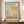 May include: Framed exhibition poster featuring Mark Rothko's abstract geometric artwork in warm earth tones - yellows, oranges, and grays in layered rectangular blocks. Poster displays gallery information and exhibition dates. Shown in thin brown frame on wooden credenza beside white ceramic vase and stacked books against cream paneled wall.
