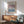 a living room with a wooden cabinet, a green armchair, and a wooden coffee table. Above the cabinet, there is a framed poster of Mark Rothko's artwork displayed on the wall.